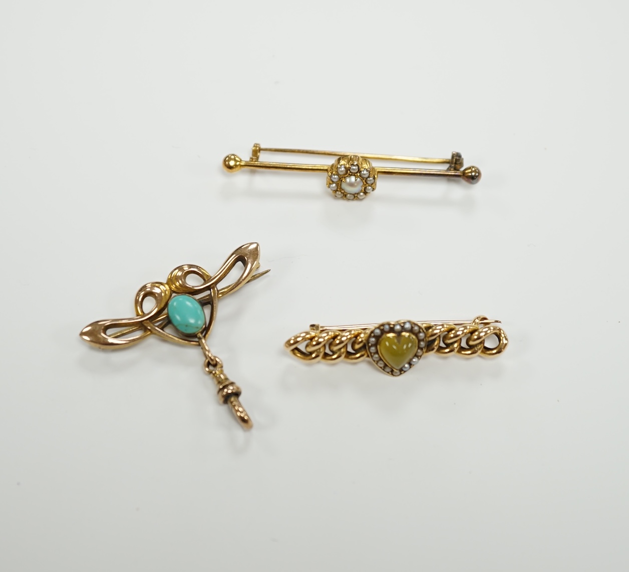 An Edwardian Art Nouveau 9ct gold and turquoise set brooch, width 38mm, a yellow metal (stamped 20) and seed pearl cluster set bar brooch and one other yellow metal and gem set brooch.